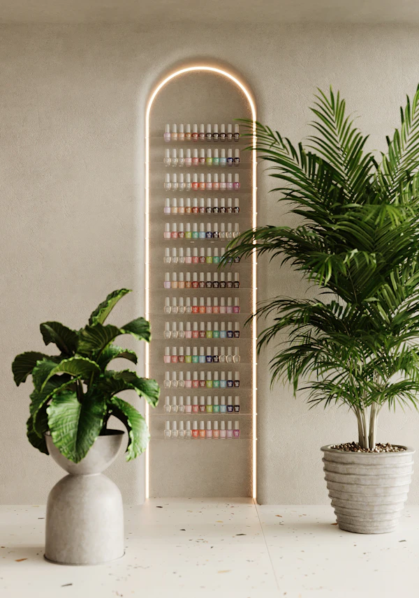 Muro de esmaltes en forma de arco iluminado, con plantas a los lados en un estudio claro