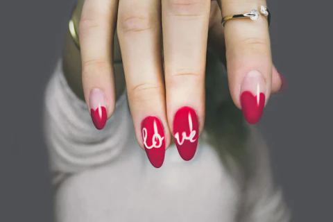 Uñas almendradas rojas con la palabra love pintada a mano