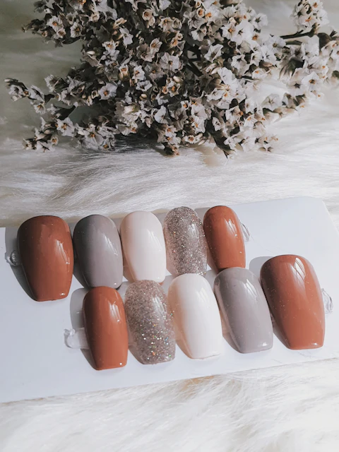 Muestrario de tips de uñas en tonos tierra, nude y glitter