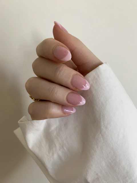 Mano con uñas almendradas en rosa pálido sosteniendo una tela de lino